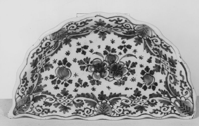 Halfcirkelvormig schoteltje versierd met bladwerk,bloemen en motieven