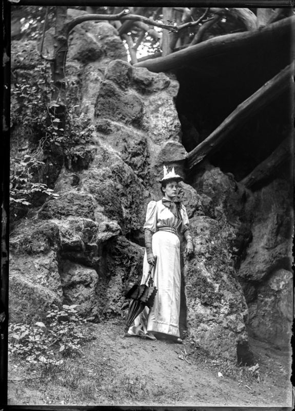 Marie Dastot, épouse t'Serstevens, debout à côté du pont rustique du bois de la Cambre