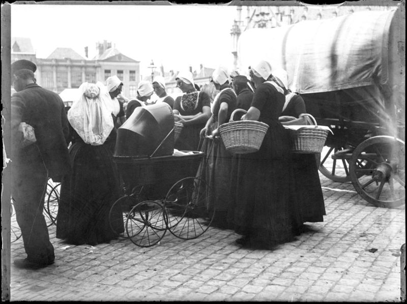 Geklede vrouwen met mand en babywagen