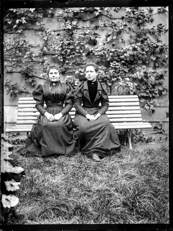 Deux jeunes femmes assises sur un banc dans un jardin