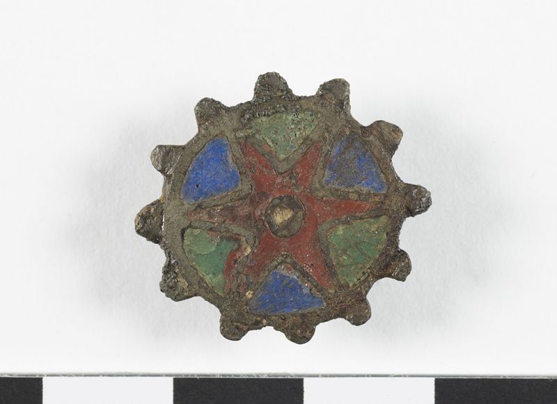 Fibule géométrique plate émaillée à charnière, en forme de cercle orné d'un motif en étoile et entouré de douze petites protubérances