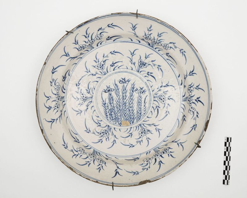 Plat en faïence de Delft au décor de tiges fleuries dans un médaillon