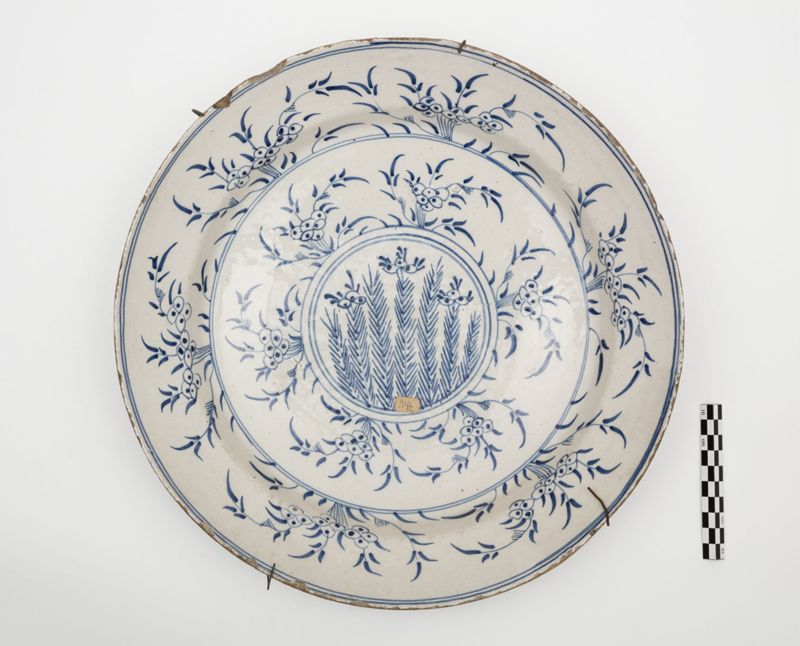 Plat en faïence de Delft au décor de tiges fleuries dans un médaillon