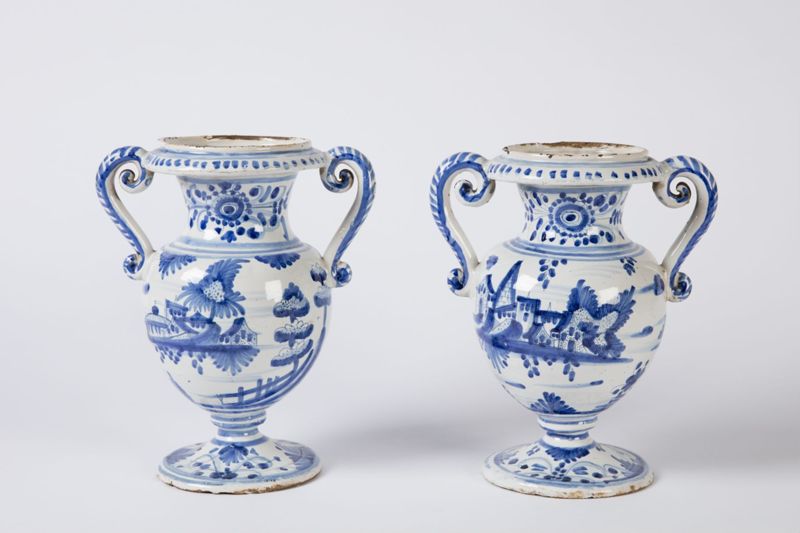 Paire de vases en faïence sur piédouche à deux anses à enroulements à décor de bouquets de fleurs et de fruits