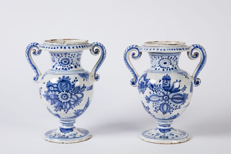 Paire de vases en faïence sur piédouche à deux anses à enroulements à décor de bouquets de fleurs et de fruits