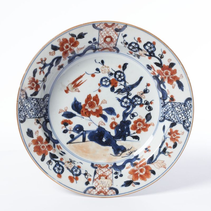 Assiette en porcelaine au décor polychrome de barrière fleurie et d’un oiseau