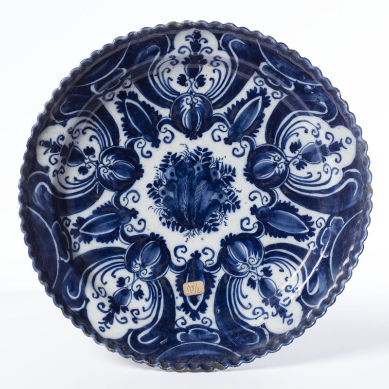 Plat festonné en faïence de Delft au décor de cinq réserves de fleurs et de lambrequins